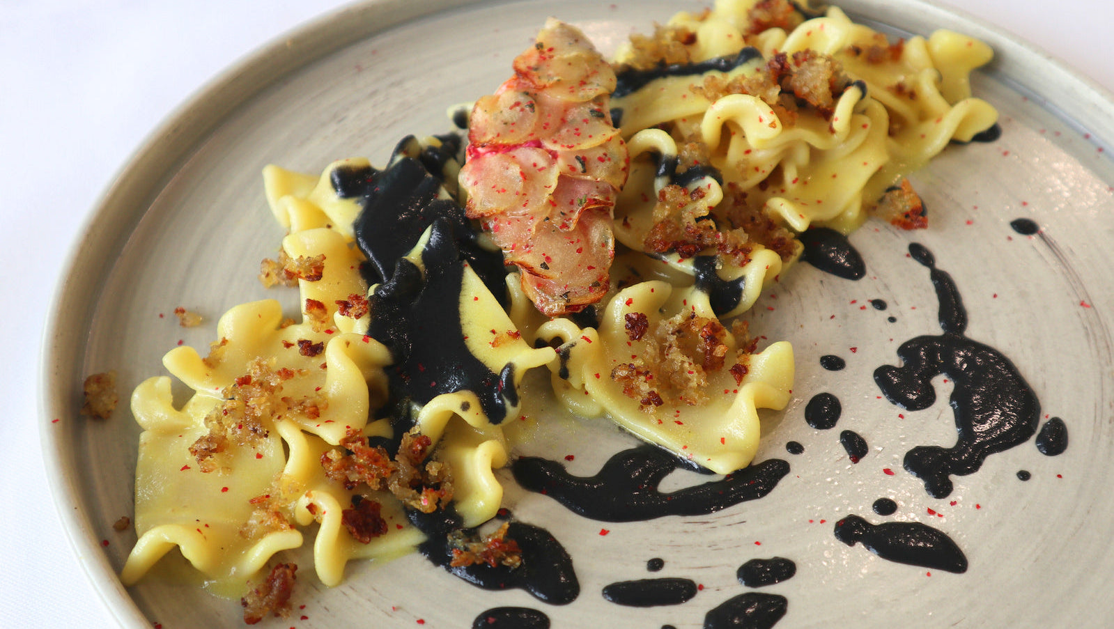 Stracci toscani allo zafferano con triglia in crosta di patate, salsa al nero di seppia e crumble di patate